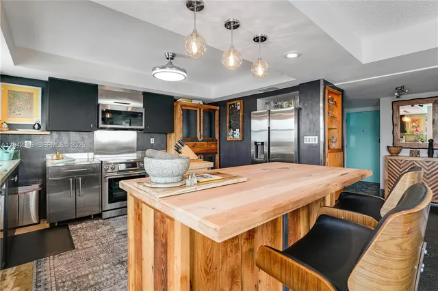 a kitchen with stainless steel appliances kitchen island granite countertop a stove a sink dishwasher and a refrigerator with wooden floor