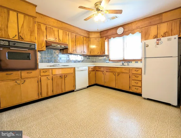 a kitchen with stainless steel appliances granite countertop a refrigerator a sink dishwasher a stove with white cabinets and wooden floor