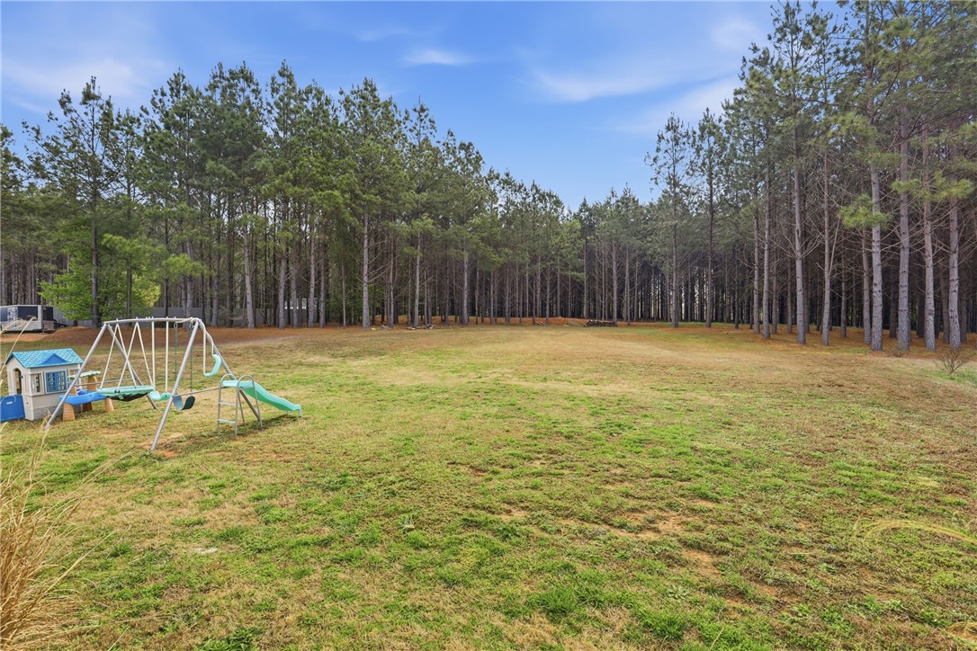 127 West Stewart Street Pelzer, SC 29669 - Photo 12 of 23 Expansive green yard with mature trees, offering ample space for outdoor activities and future enhancements.