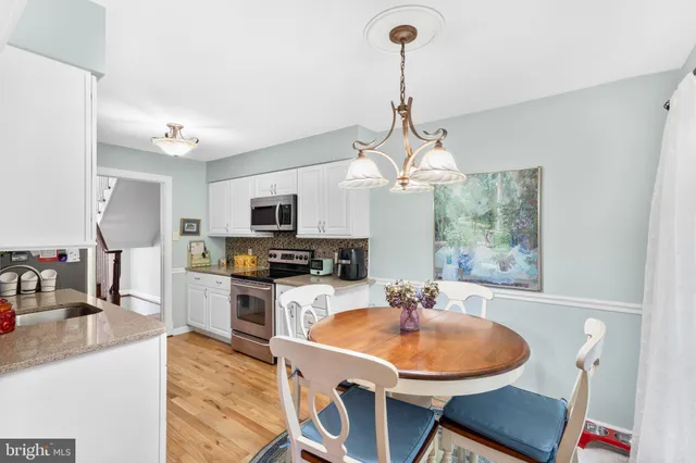a kitchen with a dining table chairs stainless steel appliances and cabinets