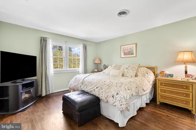 a bedroom with bed table and flat screen tv