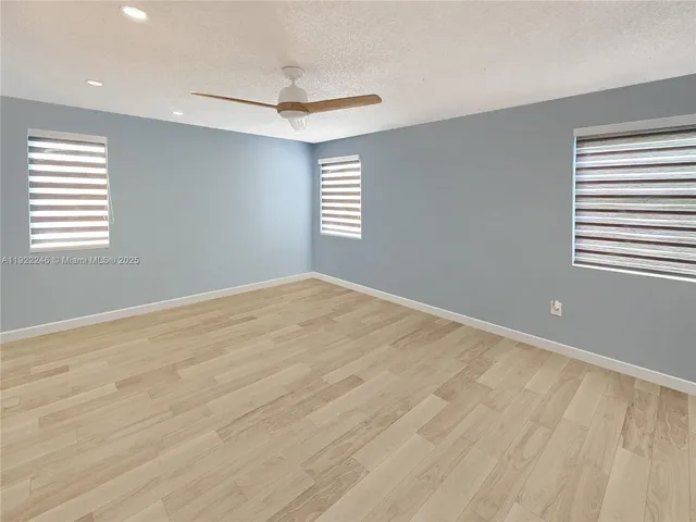 an empty room with windows and fan