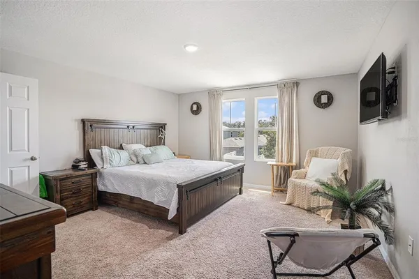 a bedroom with a bed table chair and a flat screen tv