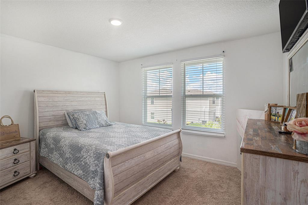13005 Upward Place Riverview, FL 33579 - Photo 15 of 27 a bedroom with a large bed and a flat tv screen on dresser