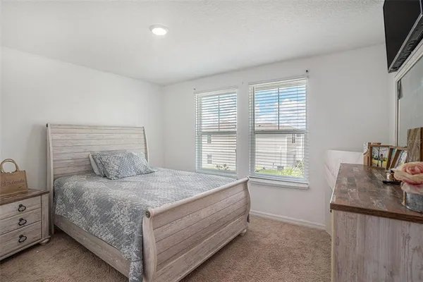 a bedroom with a large bed and a flat tv screen on dresser