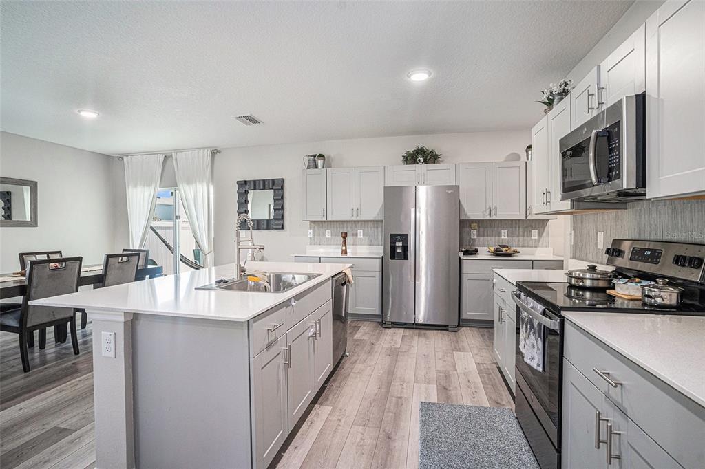13005 Upward Place Riverview, FL 33579 - Photo 8 of 28 a kitchen with stainless steel appliances granite countertop a stove top oven a sink a refrigerator and white cabinets