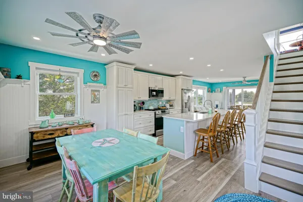 a kitchen with stainless steel appliances granite countertop a stove a refrigerator a microwave oven with white cabinets and wooden floor