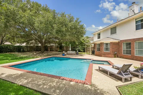 a view of swimming pool with lawn chairs and wooden fence