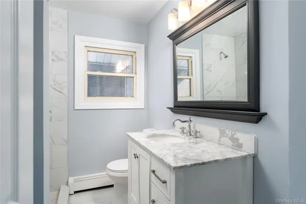 a bathroom with a granite countertop toilet sink and mirror