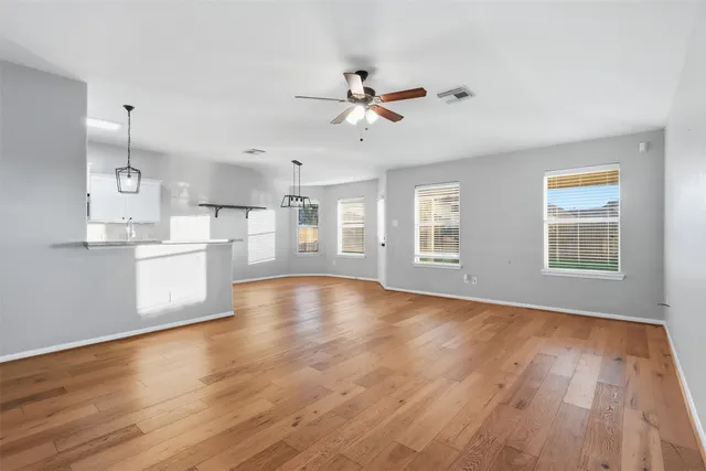 a view of an empty room with window and wooden floor