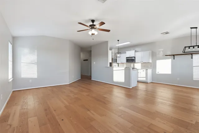 a view of a kitchen with a dishwasher a kitchen island hardwood floor and a window
