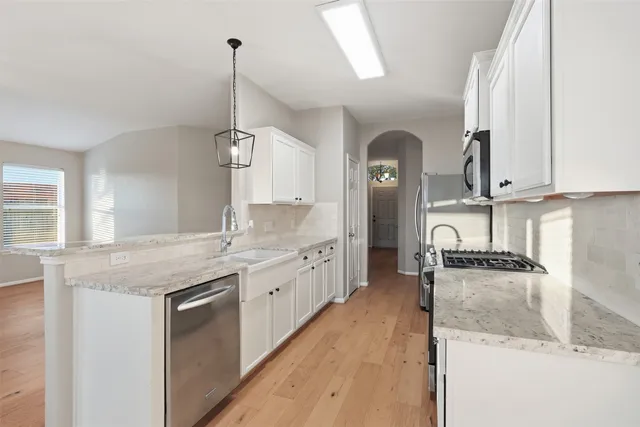 a kitchen with granite countertop a sink and dishwasher a stove top oven with wooden floor