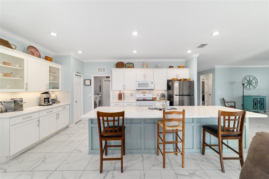 7765 Southwest 80th Pl Road Ocala, FL 34476 - Photo 17 of 37 a kitchen with stainless steel appliances kitchen island granite countertop a dining table chairs and a refrigerator