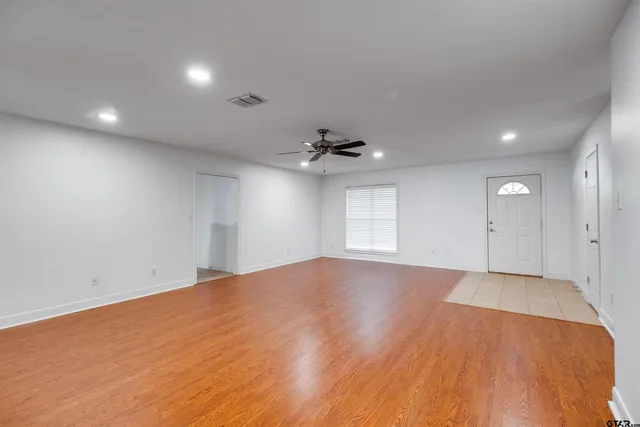 an empty room with windows and chandelier fan