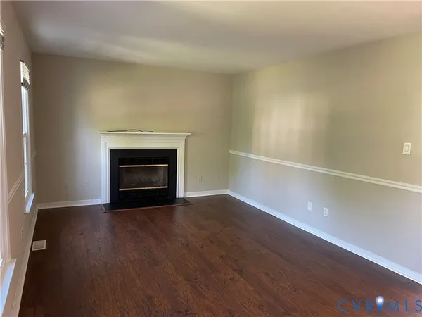 a view of an empty room with wooden floor fireplace and a window