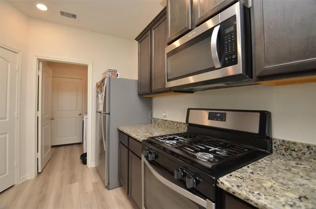 a kitchen with stainless steel appliances granite countertop a stove and a microwave