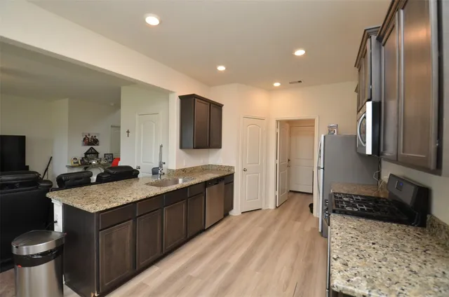 a kitchen with stainless steel appliances granite countertop a sink stove and refrigerator