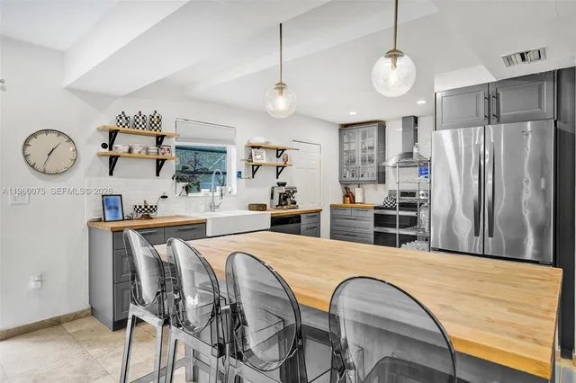a kitchen with stainless steel appliances granite countertop a table chairs and a refrigerator