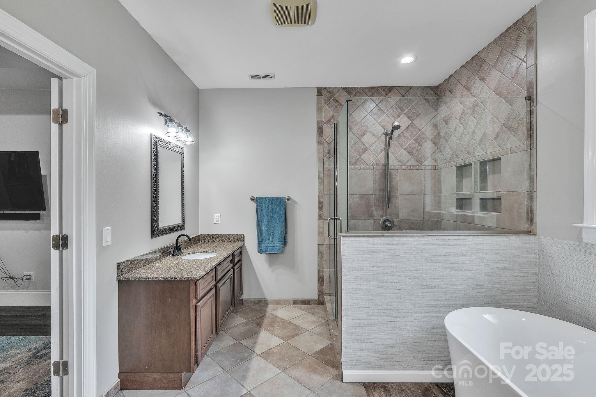 220 Alvin Hough Road Midland, NC 28107 - Photo 18 of 46 a bathroom with a granite countertop sink a mirror and a shower