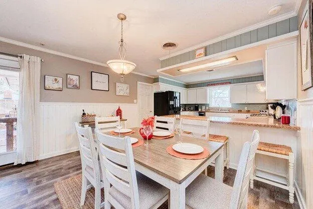 a open dining room with stainless steel appliances a table and chairs