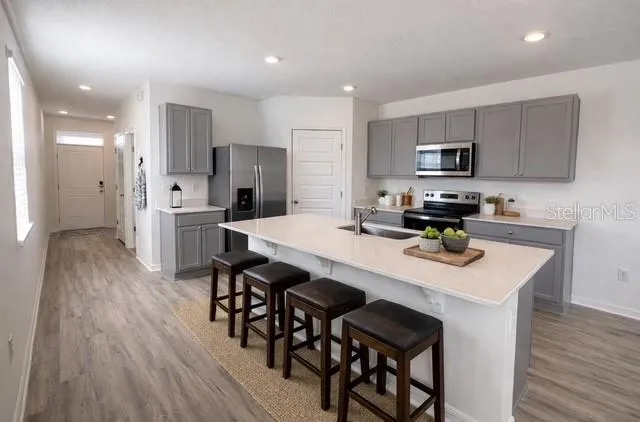 a kitchen with stainless steel appliances a dining table chairs stove refrigerator and cabinets