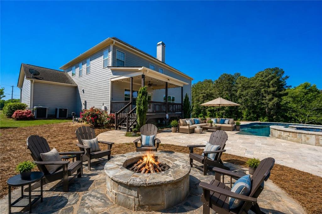 760 Carl Davis Road Northwest Monroe, GA 30656 - Photo 32 of 40 a view of a patio with couches table and chairs under an umbrella with potted plants and wooden fence
