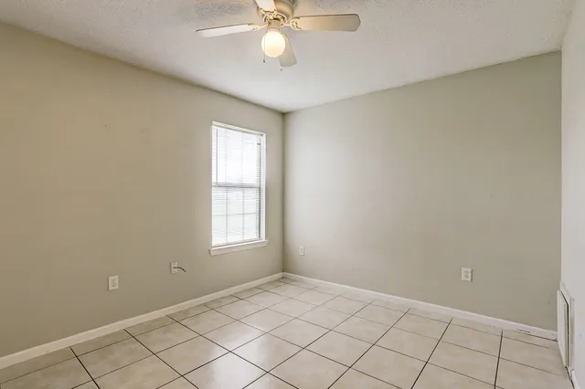 an empty room with windows and fan
