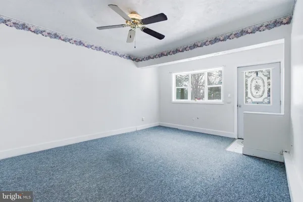 an empty room with windows and fan