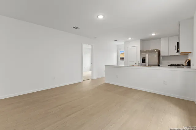 a large white kitchen with kitchen island a sink stainless steel appliances and cabinets