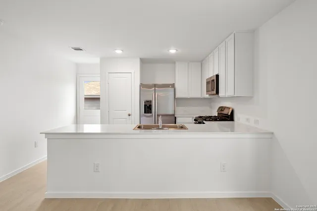 a kitchen with kitchen island white cabinets and refrigerator