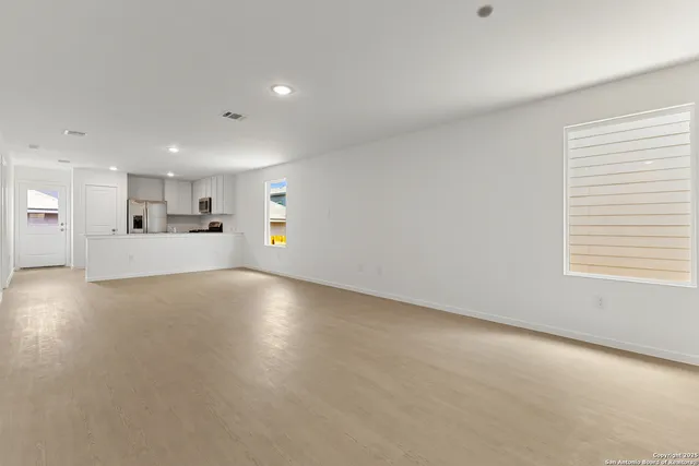 a view of empty room with kitchen and window
