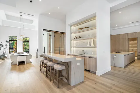 a large white kitchen with stainless steel appliances granite countertop a lot of counter space and a large window
