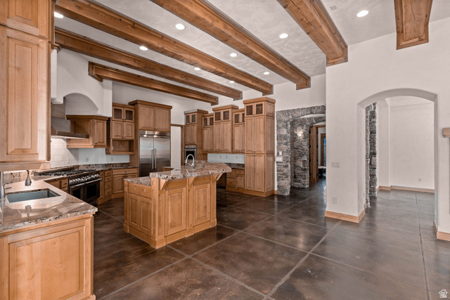 2464 East Granite Way St. George, UT 84790 - Photo 45 of 106 Kitchen with arched walkways, beamed ceiling, glass fronted cabinets, a kitchen island with sink, and high end appliances