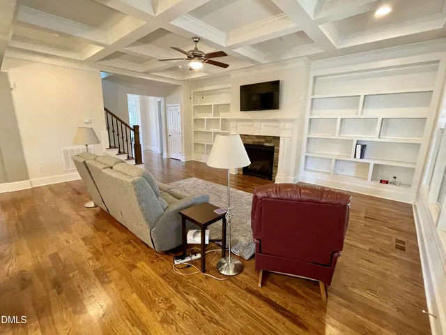a view of a hallway with wooden floor and a living room