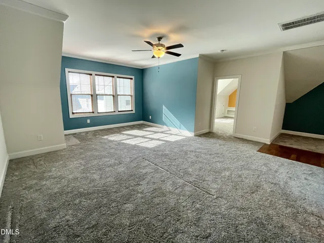 an empty room with chandelier fan and windows