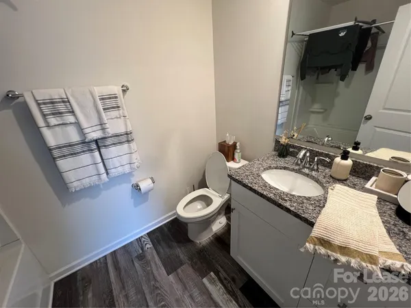 a bathroom with a granite countertop toilet sink and mirror