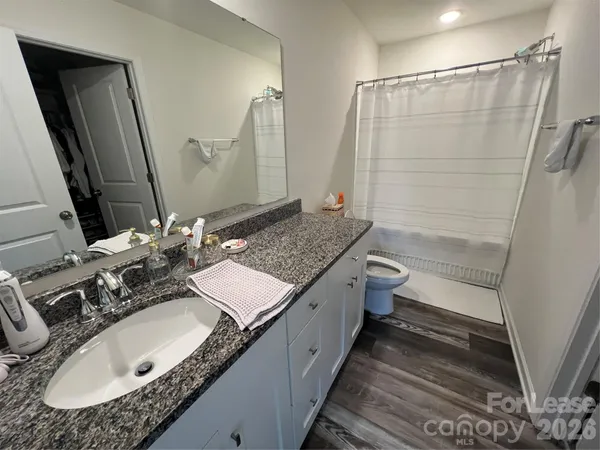 a bathroom with a granite countertop sink a toilet a mirror and shower