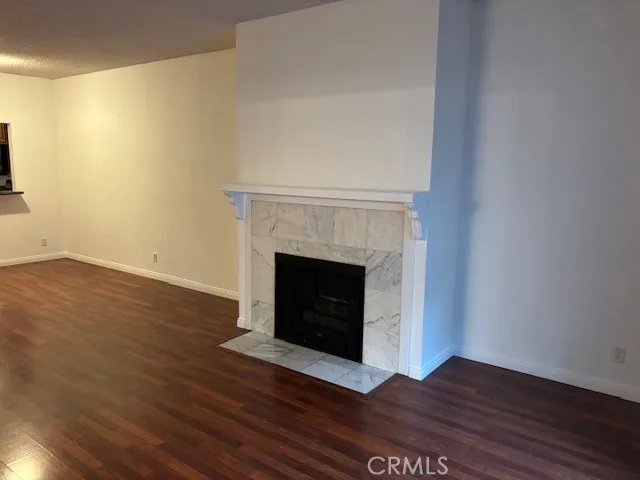 a view of an empty room with wooden floor and a fireplace