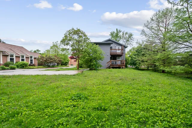 a view of a house with a small yard plants and large trees