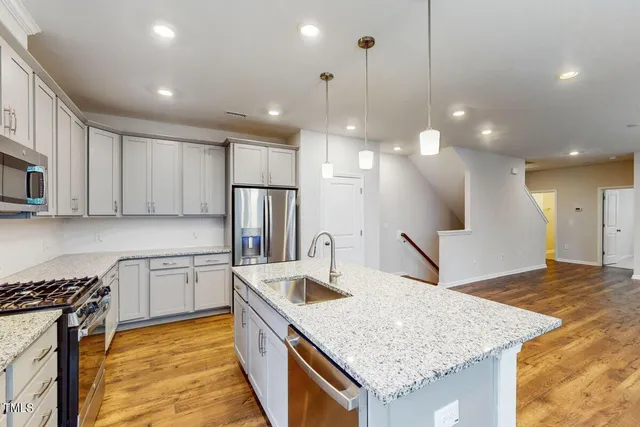 a kitchen with stainless steel appliances granite countertop a sink a stove a refrigerator and a oven