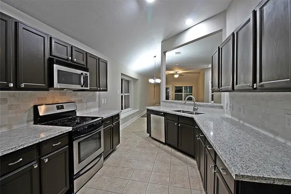 a large kitchen with granite countertop a stove top oven microwave and cabinets