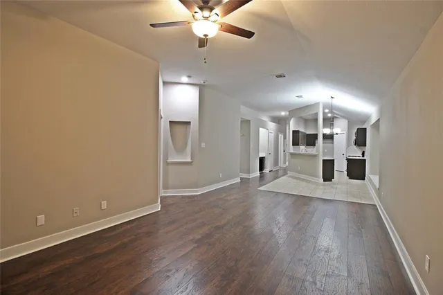 an empty room with wooden floor and a ceiling fan