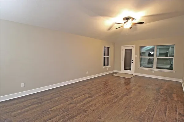 a view of an empty room with a window and wooden floor