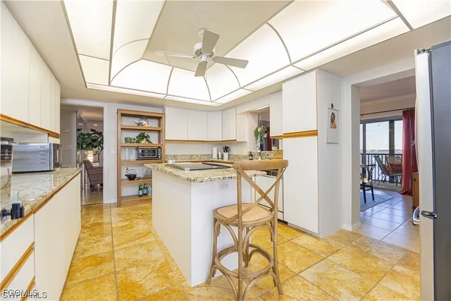 a kitchen with stainless steel appliances kitchen island granite countertop a table chairs in it and a window