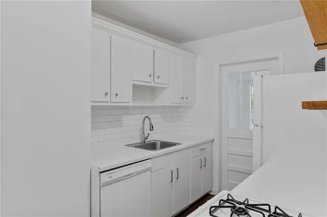 a kitchen with white cabinets and sink