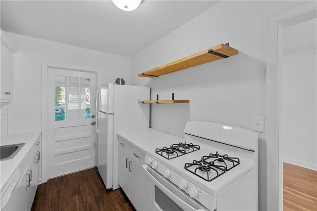 a kitchen with a refrigerator a stove and wooden floor