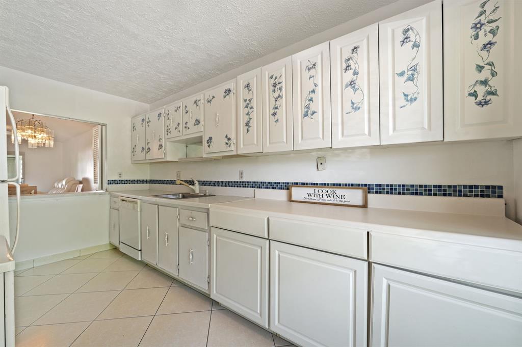 1271 Northwest 18th Avenue, Unit 5C Delray Beach, FL 33445 - Photo 10 of 36 a kitchen with granite countertop white cabinets and white appliances