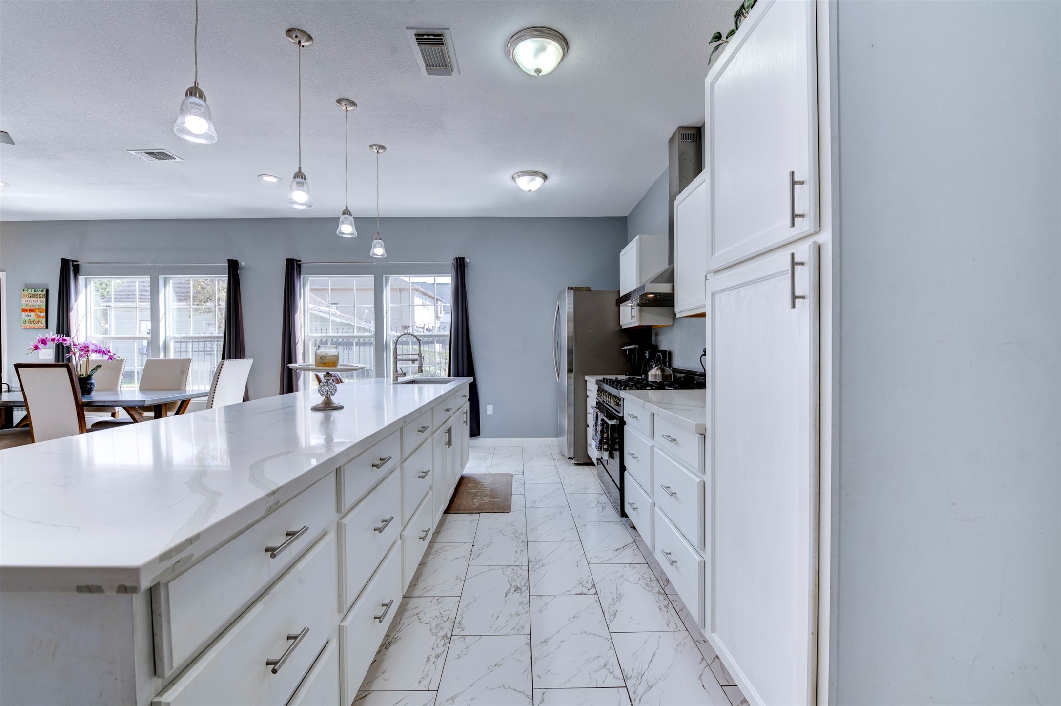 301 Tabor Street Houston, TX 77009 - Photo 10 of 33 a large white kitchen with center island and stainless steel appliances