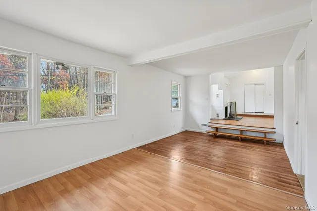 a view of empty room with wooden floor and window
