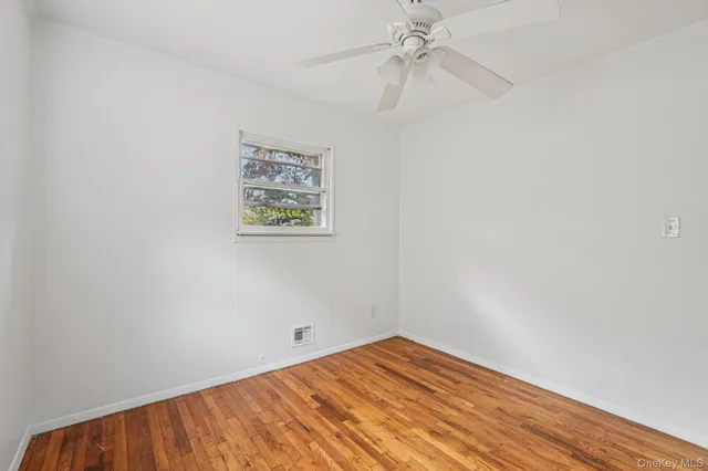 an empty room with a fan and a window
